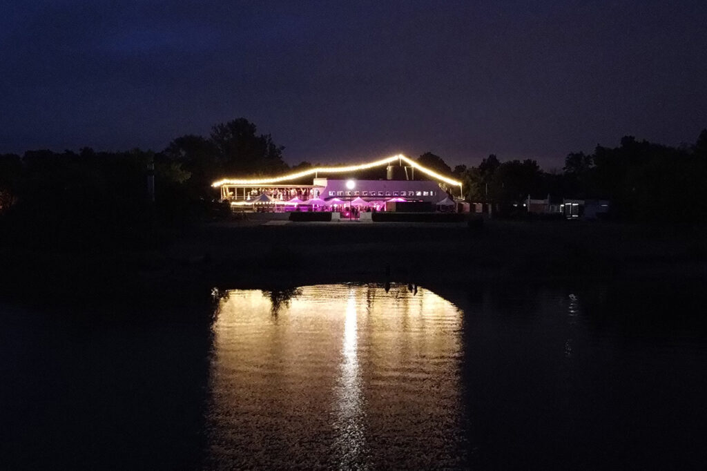 Das Bild zeigt die beleuchtete Eventlocation amSee im Dunkeln vom Wasser aus.