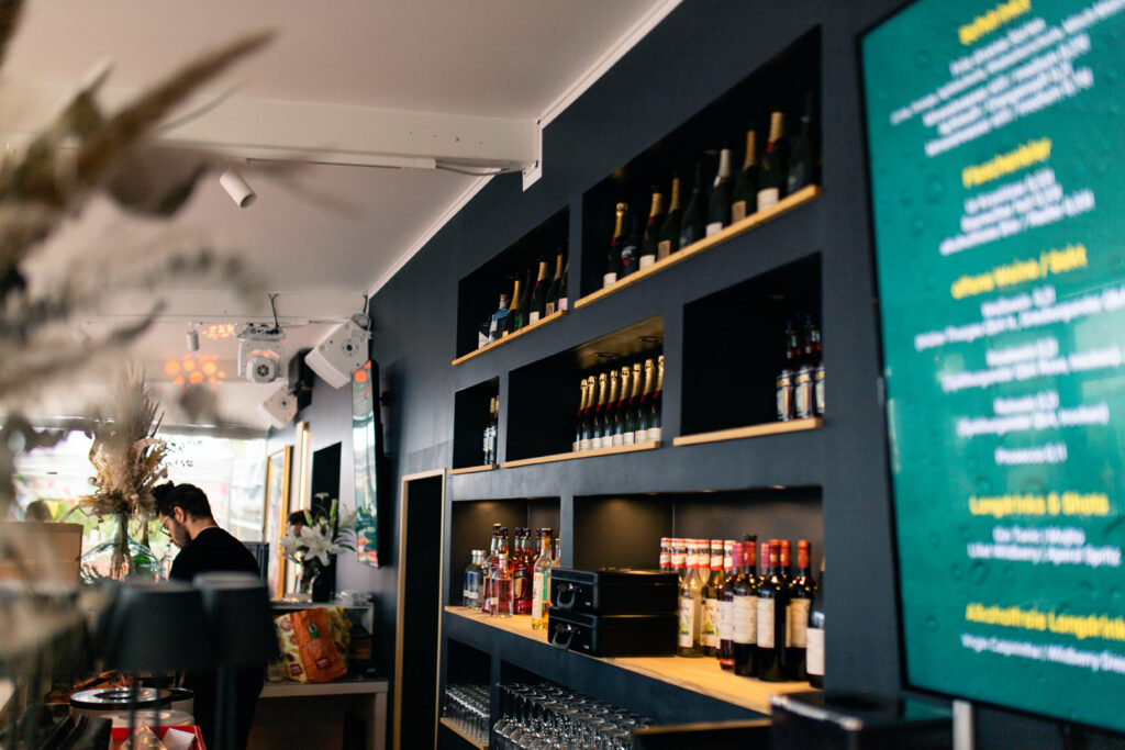 Das Barregal im Wintergarten, daneben eines der Displays, auf denen die digitale Getränkekarte gezeigt wird.