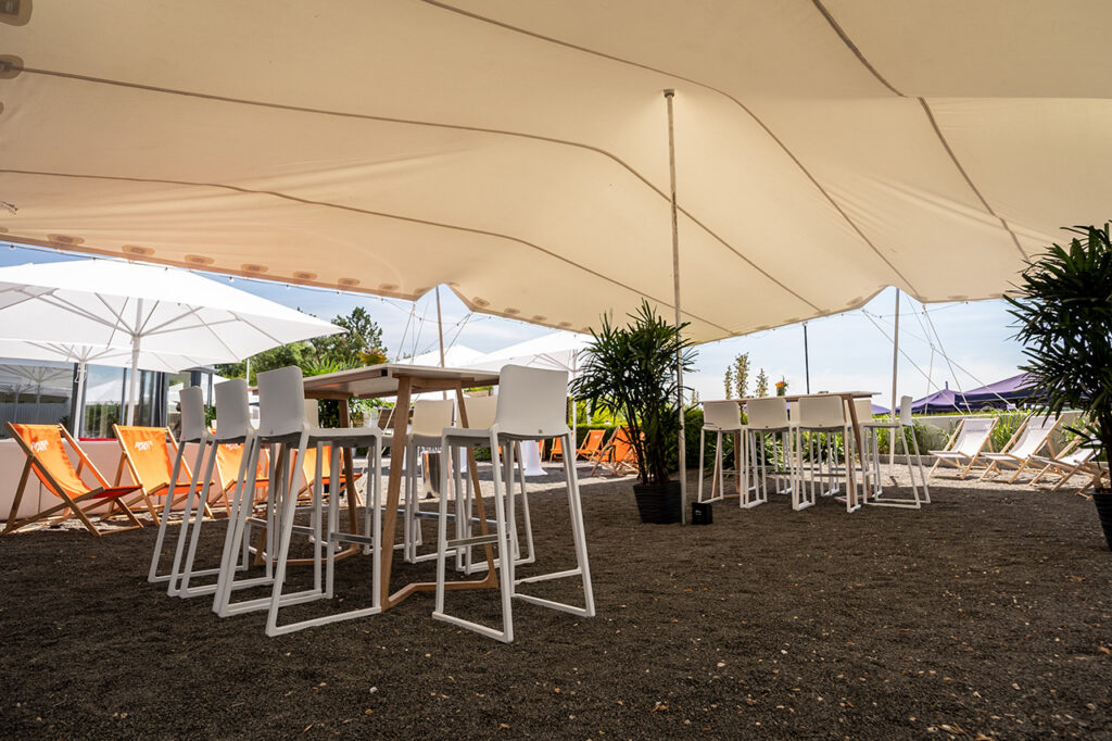 Sitzgruppe unter einem großen Sonnensegel vor der amSee Eventlocation.