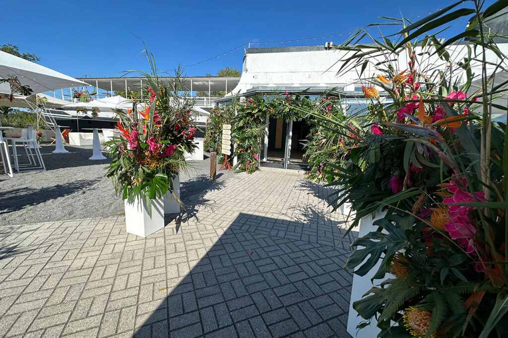 Üppiger Blumenschmuck sorgt für Akzente bei einer Hochzeit am See. Hier: Eingangsbereich vor dem Wintergarten und Teile der Terrasse.