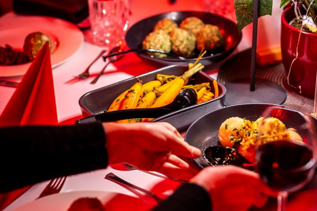 Eine Person füllt ihren Teller mit Knödeln und anderen weihnachtlichen Speisen.